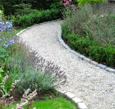 a gravel path surrounded by flowers and greenery