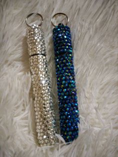 two key chains with beads on them laying on a white furnishing area next to each other