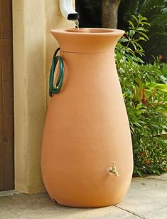 a large brown vase sitting on top of a cement floor next to a planter