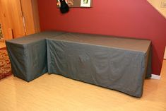 a long table with a gray cover on it in front of a red wall and stairs