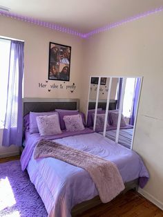 a bed with purple sheets and pillows in a room