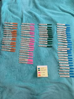 several different colored toothbrushes laying on a blue towel next to a small card