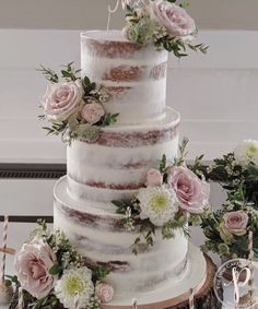 a three tiered wedding cake with pink flowers on top and greenery around it