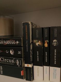 several books are stacked on top of each other in front of a lamp and book shelf