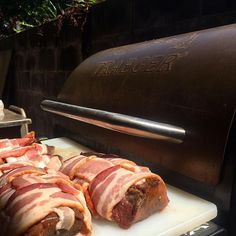 meat wrapped in bacon is being cooked on a grill