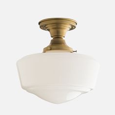 a light fixture with a white glass shade on the bottom and an antique brass finish