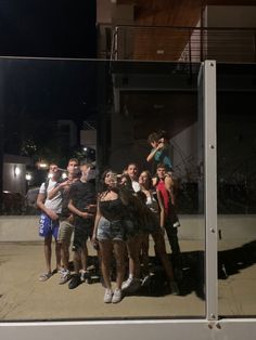 a group of young people standing next to each other in front of a building at night