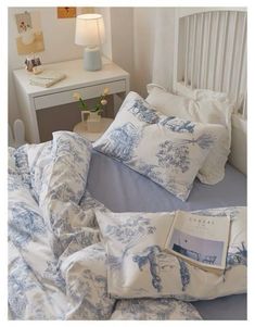 a bed with blue and white pillows on top of it next to a night stand