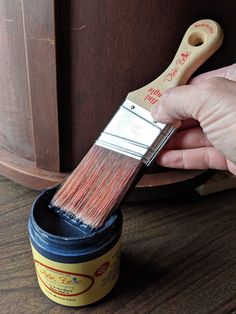 a person holding a paint brush over a can