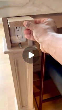 a person is holding the door handle on a kitchen cabinet with an electrical outlet in it