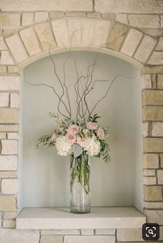 a vase filled with flowers sitting on top of a mantle