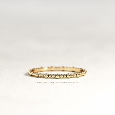 a yellow gold ring with small dots on the outside and inside, sitting on a white surface