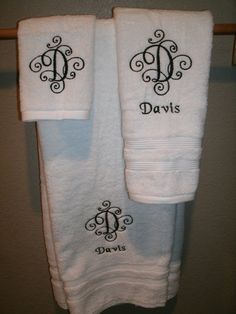 two white towels with black monogrammed initials on them hanging from a towel rack