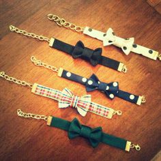 four different types of bow ties on a wooden table with gold chains and chain around them