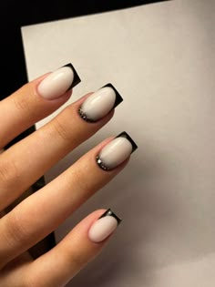 a woman's hand with black and white nail polish on her nails, next to a cell phone