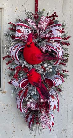 a christmas wreath with two red birds hanging from it's side on a door