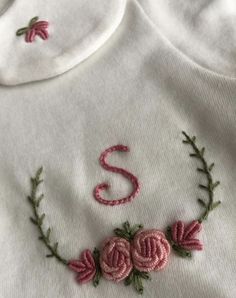 a white shirt with pink flowers and the letter s embroidered on it's chest