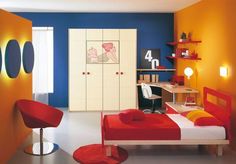 a bedroom with orange and blue walls, white furniture and a red chair in the corner