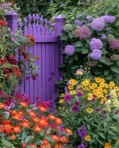 a purple fence surrounded by colorful flowers and greenery