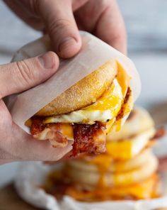 a person is holding up a bacon and cheese sandwich