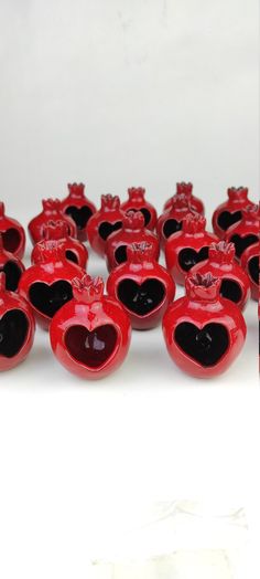 many red heart shaped candies are lined up on a white surface with black hearts