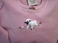 a pink sweater with white and black sheep embroidered on the front, along with flowers