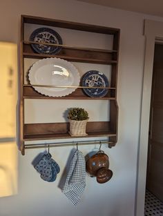 a shelf that has some plates and bowls on it, hanging from the wall next to a potted plant