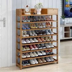 a wooden shoe rack with many pairs of shoes on it in front of a tv