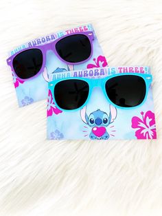 two pairs of sunglasses sitting on top of a white furry surface