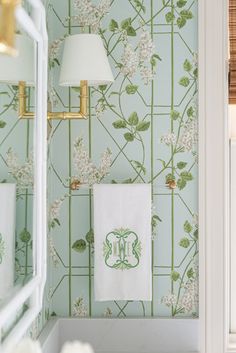 a bathroom with green and white wallpaper, gold fixtures and towels hanging on the rack