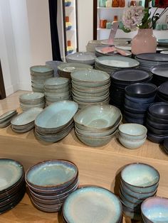 there are many plates and bowls on the shelves in this room, all stacked together