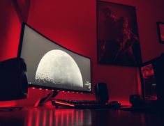 a computer monitor sitting on top of a desk in front of a red wall with pictures