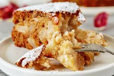 a piece of cake on a white plate with a fork and some powdered sugar