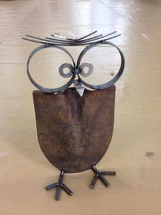 an owl made out of rusty metal with eyes and legs sitting on top of a table