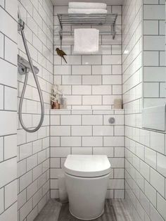 a white toilet sitting inside of a bathroom next to a walk in shower and tiled walls