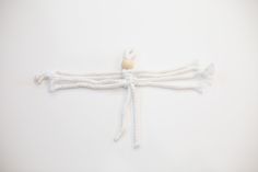 a white string tied to a wall with a wooden bead on the end and rope around it