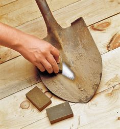 a person using a shovel to remove dirt from the floor next to a tile block