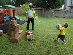 a young boy playing with a ball in the yard while an older man looks on