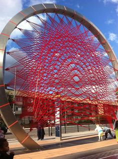 a large red sculpture sitting on the side of a road