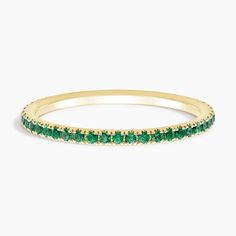 a yellow gold band with green stones