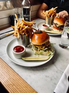 two plates with burgers and french fries on them