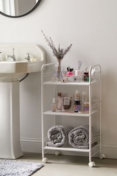 a bathroom with a sink, mirror and shelf filled with personal care items on it