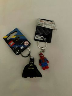 two lego keychains are sitting next to each other on a white surface,