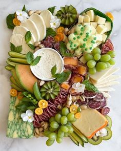 a platter filled with different types of cheeses and fruits on top of a marble table