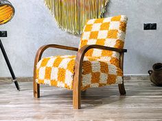 an orange and white chair sitting on top of a hard wood floor next to a lamp