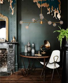 a dining room with green walls and wooden flooring, an antique table surrounded by white chairs