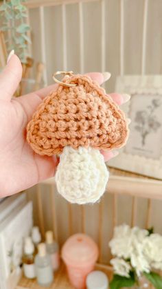 a crocheted mushroom keychain is held in the palm of someone's hand