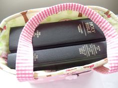 a pink and white purse with three books in it