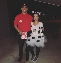 a man standing next to a woman dressed as a dalmatian and wearing a costume