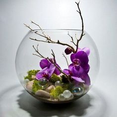 a glass bowl filled with rocks and purple flowers